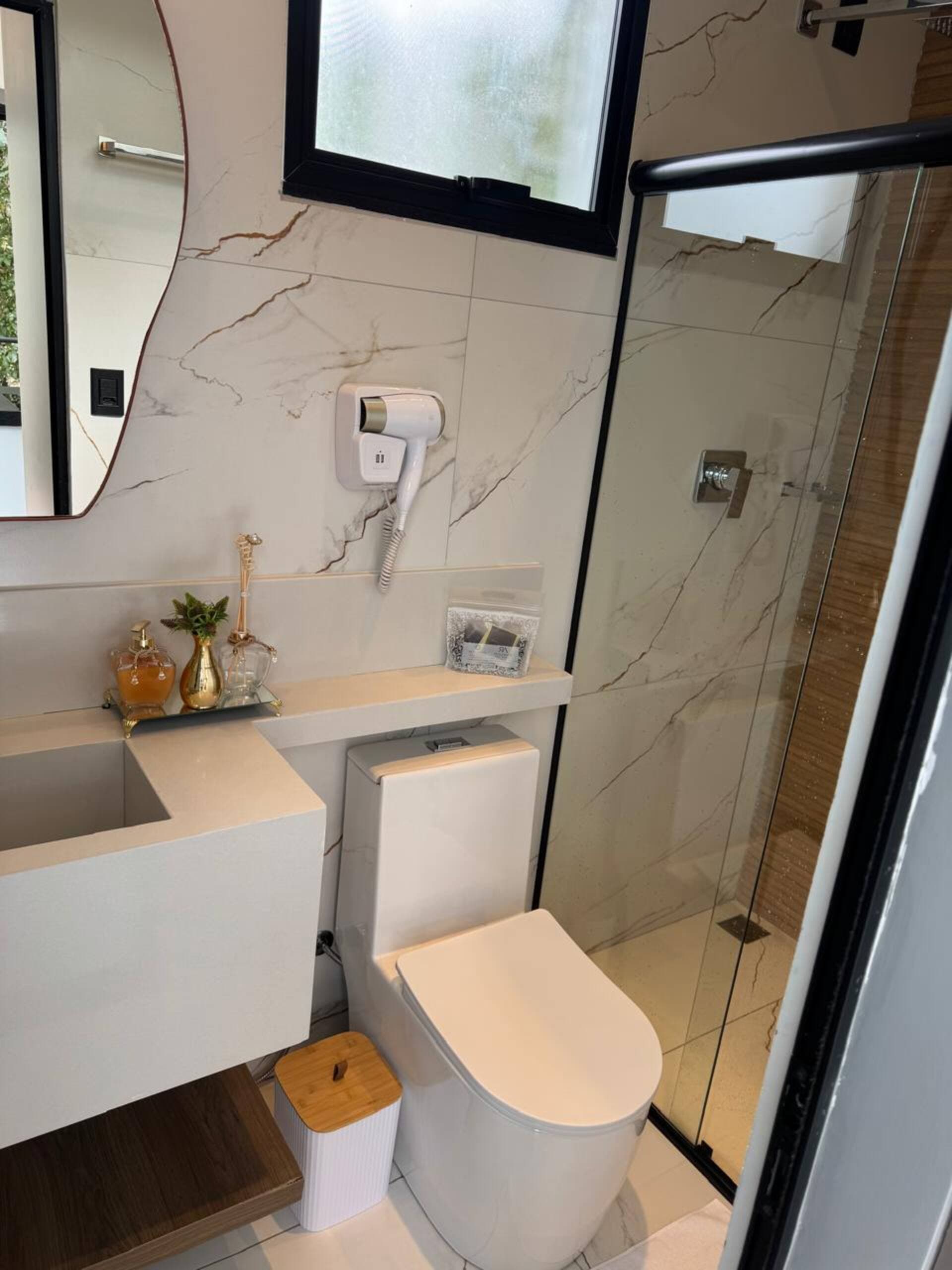 Vaso sanitário e secador de cabelo junto ao box, com revestimento marmorizado
