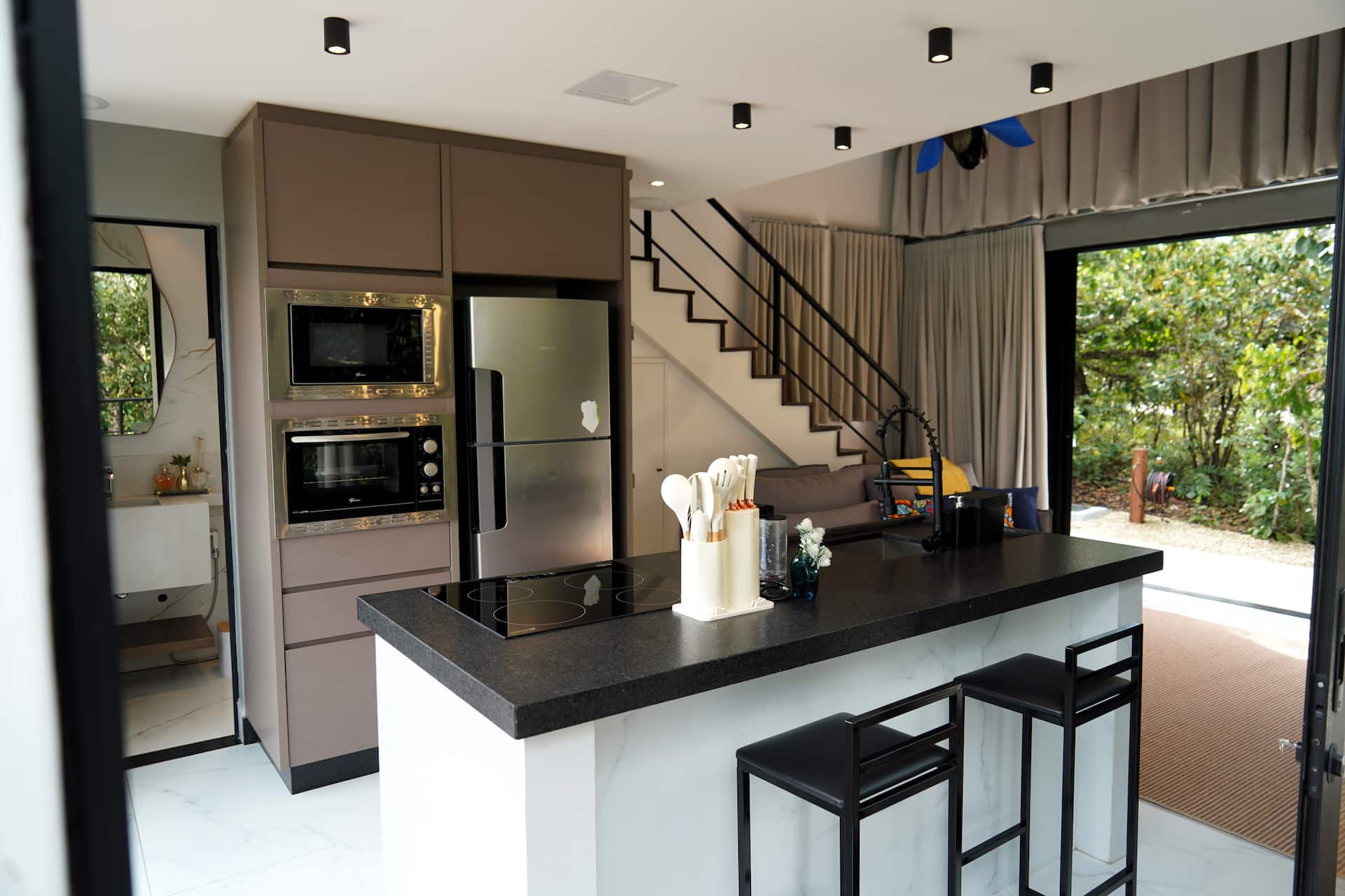 Cozinha planejada com forno e micro-ondas embutidos, geladeira inox e escada ao fundo