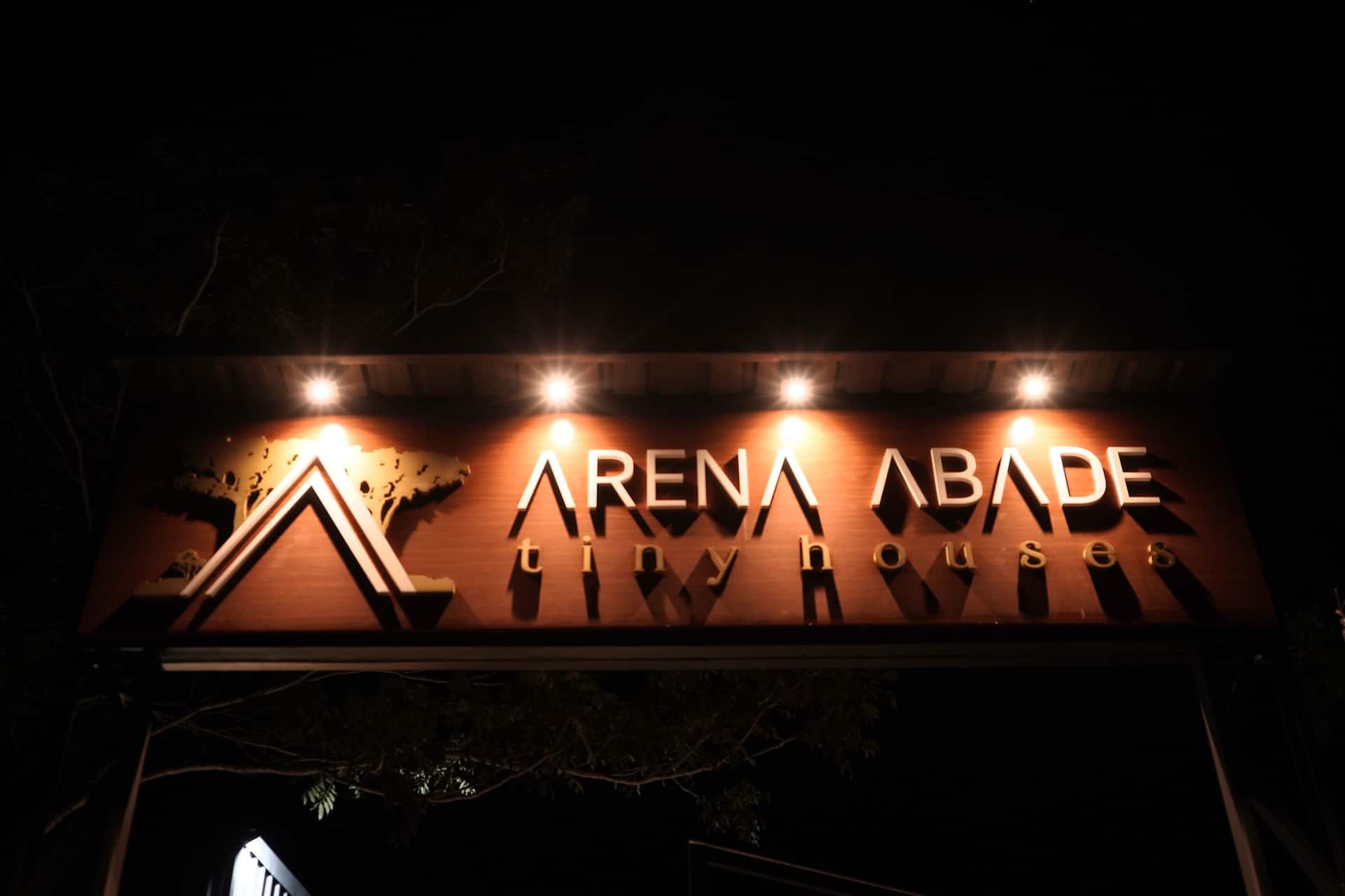 Letreiro iluminado Arena Abade sobre o revestimento em madeira, à noite